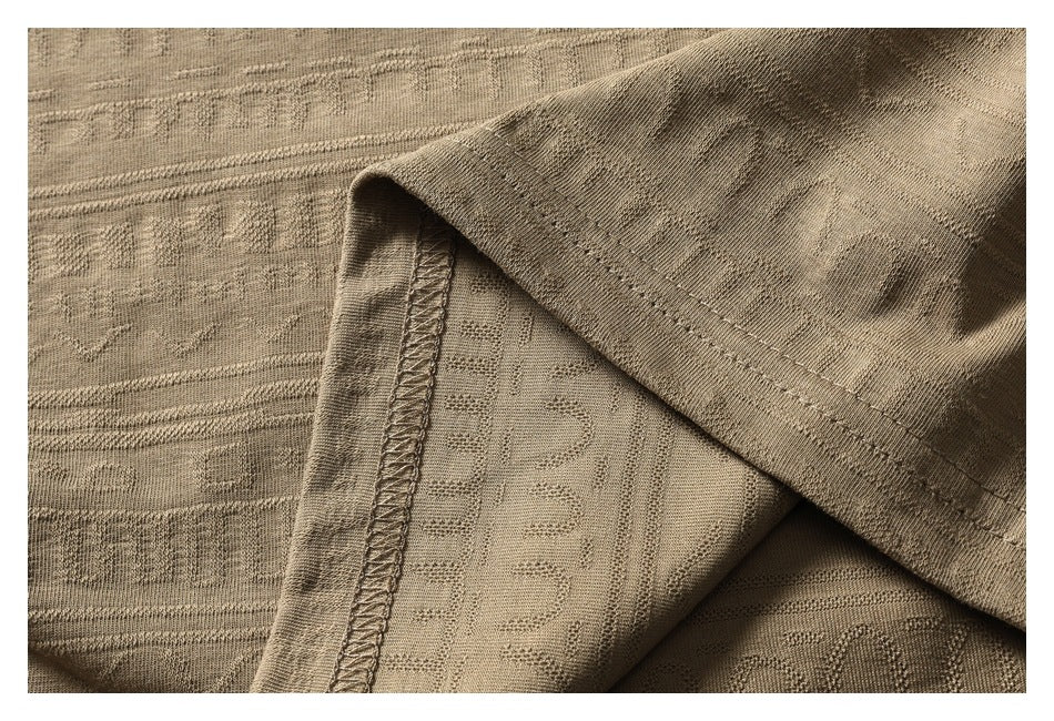 Close-up of the tan shirt fabric folded back to show its patterned underside and overlocked seam.
