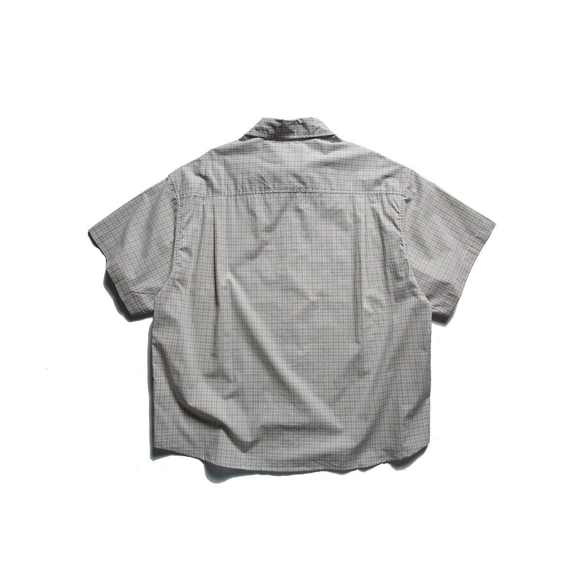 Back view of beige small-check short-sleeve shirt laid flat, showing yoke seam and pleats
