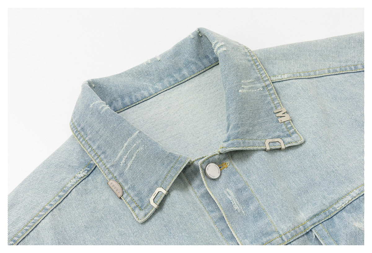 Close-up of the pointed collar, button placket and metal accents on a light-wash denim jacket.