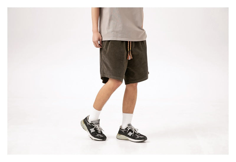 Cropped model wearing dark olive knee-length shorts with a colorful braided drawstring, shown at an angle.