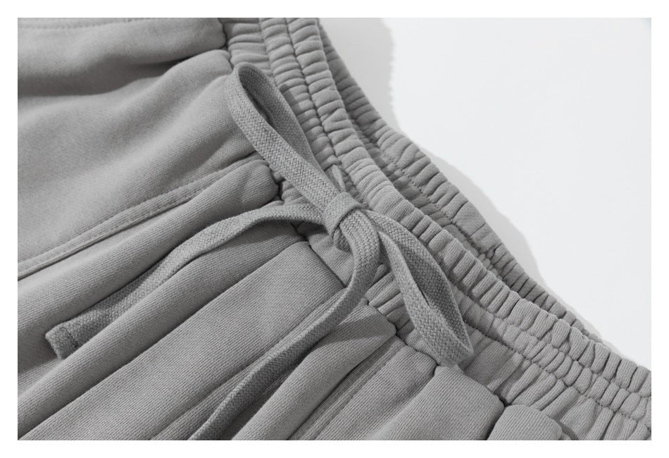Close-up of gray sweatpants showing the gathered elastic waistband and matching drawstring.