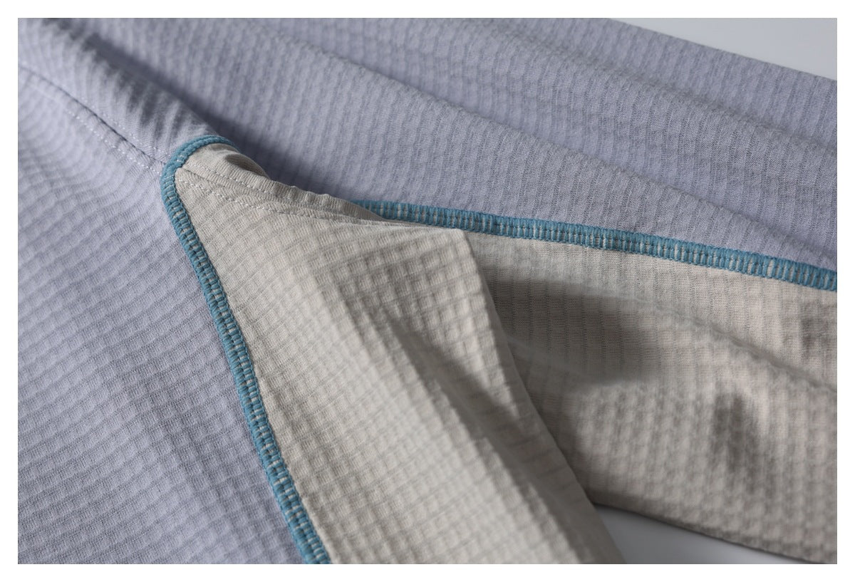 Close-up of the jacket’s interior seam and textured gray and cream fabric with teal overlock stitching.