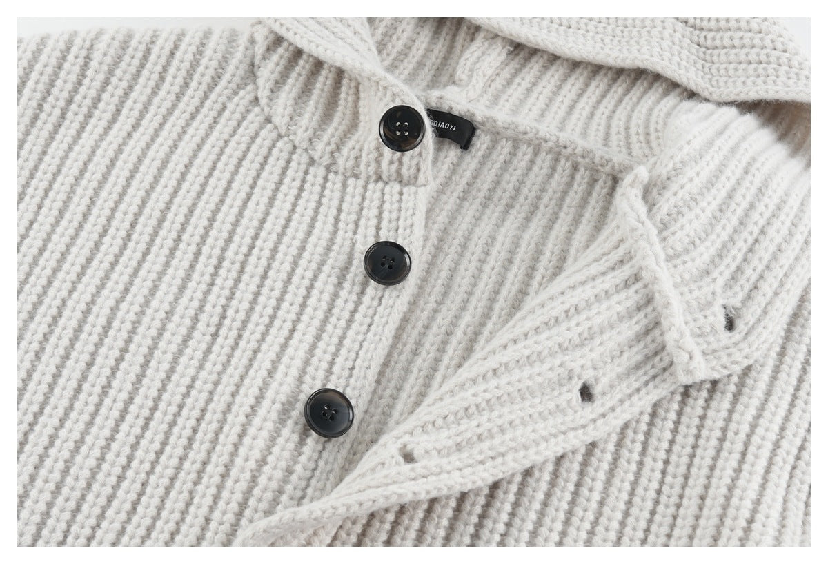 Close-up of the off-white sweater's ribbed knit, dark front buttons, and small sewn-in black label.