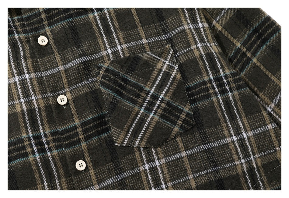 Close-up of the shirt front with a chest pocket and cream buttons against a dark plaid pattern.