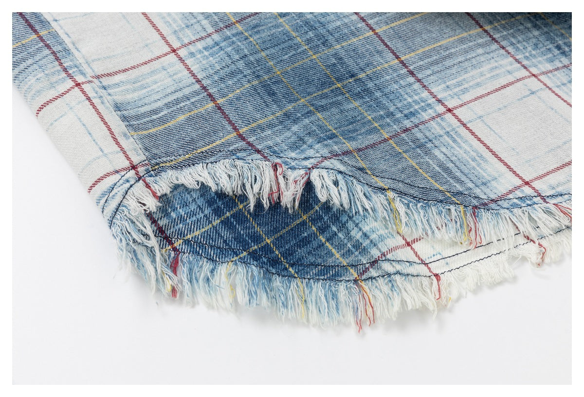 Close-up of blue, white, red, and yellow plaid fabric with a heavily frayed edge.