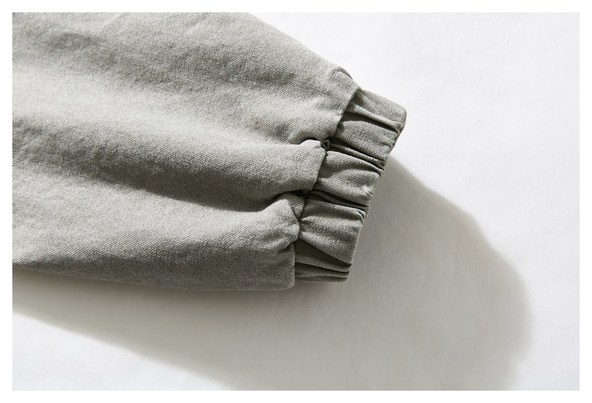 Close-up of a gray-olive woven garment ending in a gathered elastic cuff.