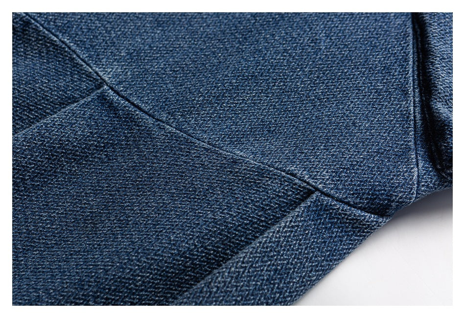 Close-up of dark blue denim panels with diagonal stitching and a folded edge.