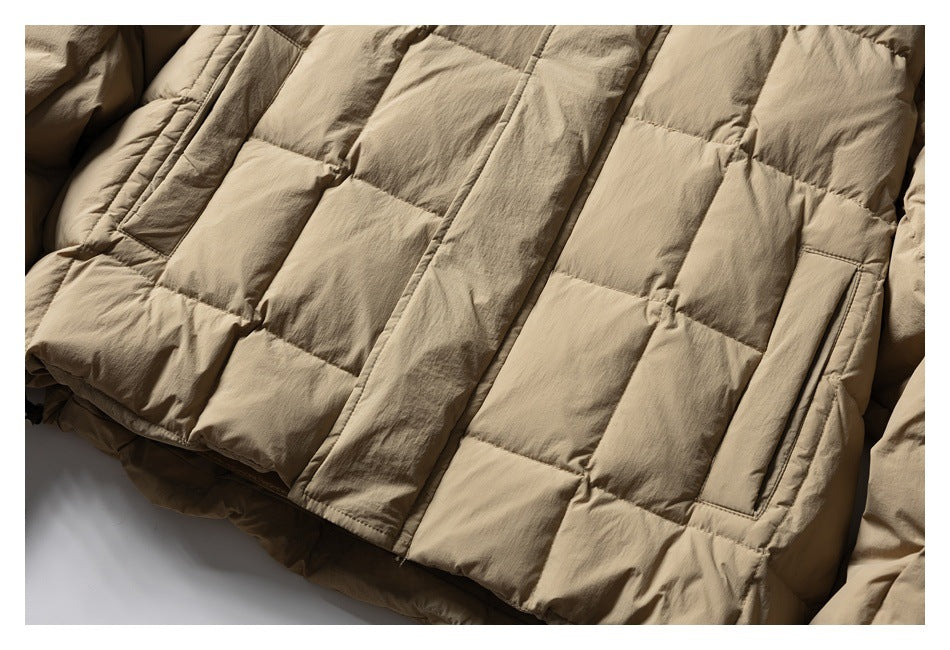 Close-up of a beige puffer jacket showing rectangular quilted panels and a vertical pocket.