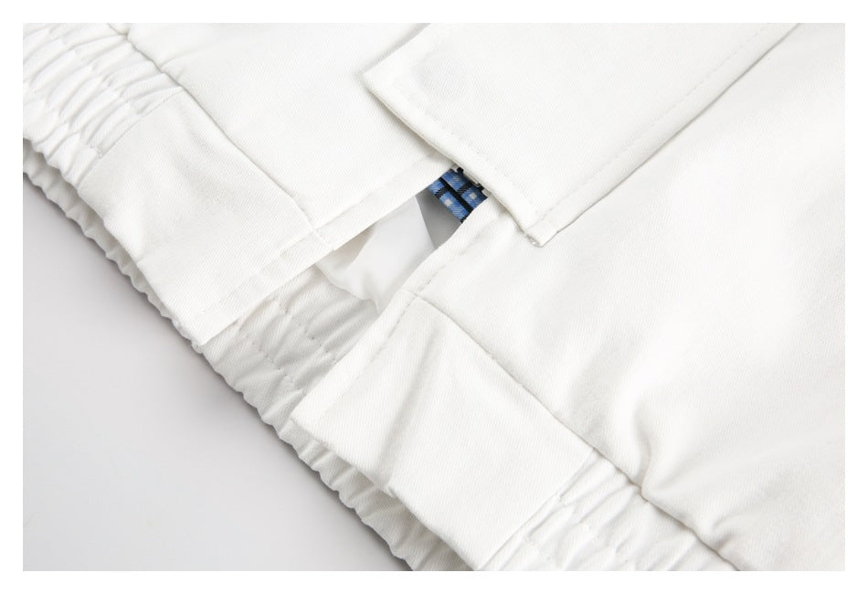 Close-up of an elastic waistband and stitched panels on a white garment, with a glimpse of blue plaid trim.