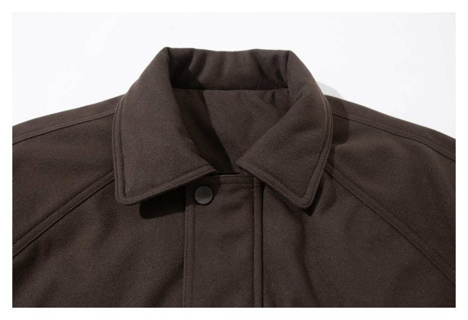 Close-up of a dark brown jacket's pointed collar, shoulder seams, and snap-button front.