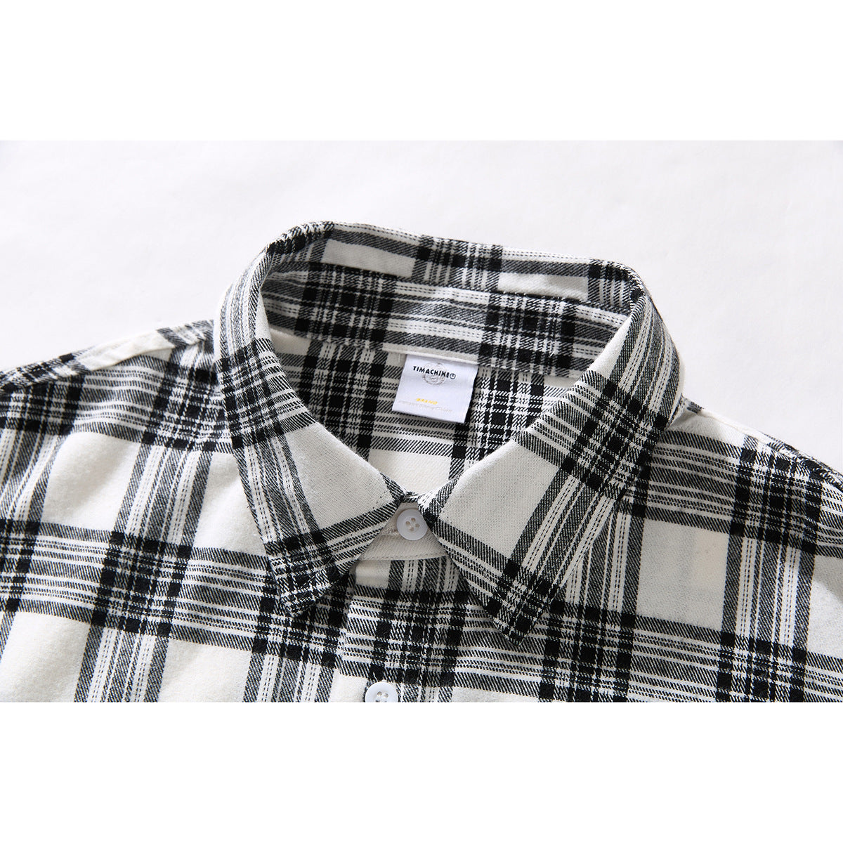 Close-up of a black-and-white plaid shirt collar, top button and inner neck label.