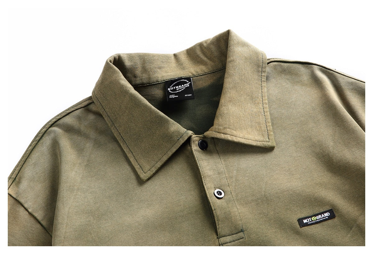 Close-up of the olive shirt front, showing its pointed collar, two-button placket, chest label, and neck tag.