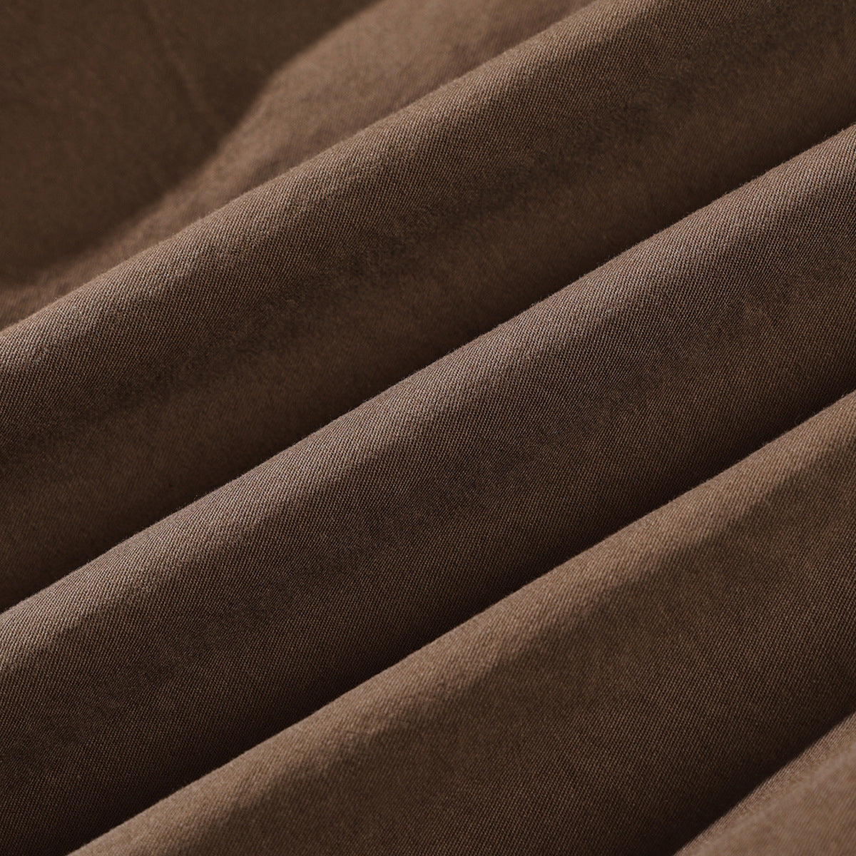 Macro view of brown fabric arranged in soft folds, showing its fine surface texture.