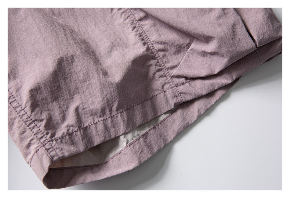 Close-up of the dusty mauve shorts' stitched hem and folded inner lining.