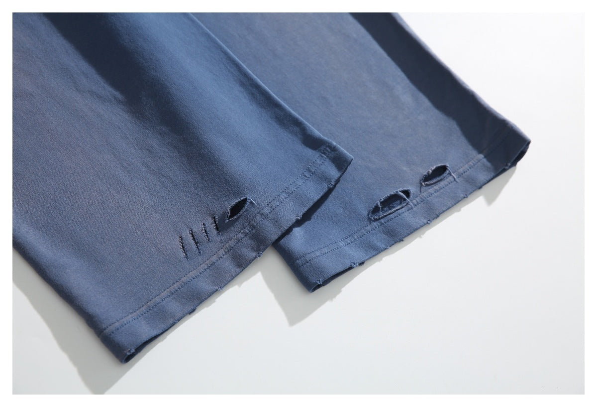 Close-up of two blue garment hems with distressed slits and visible stitching.