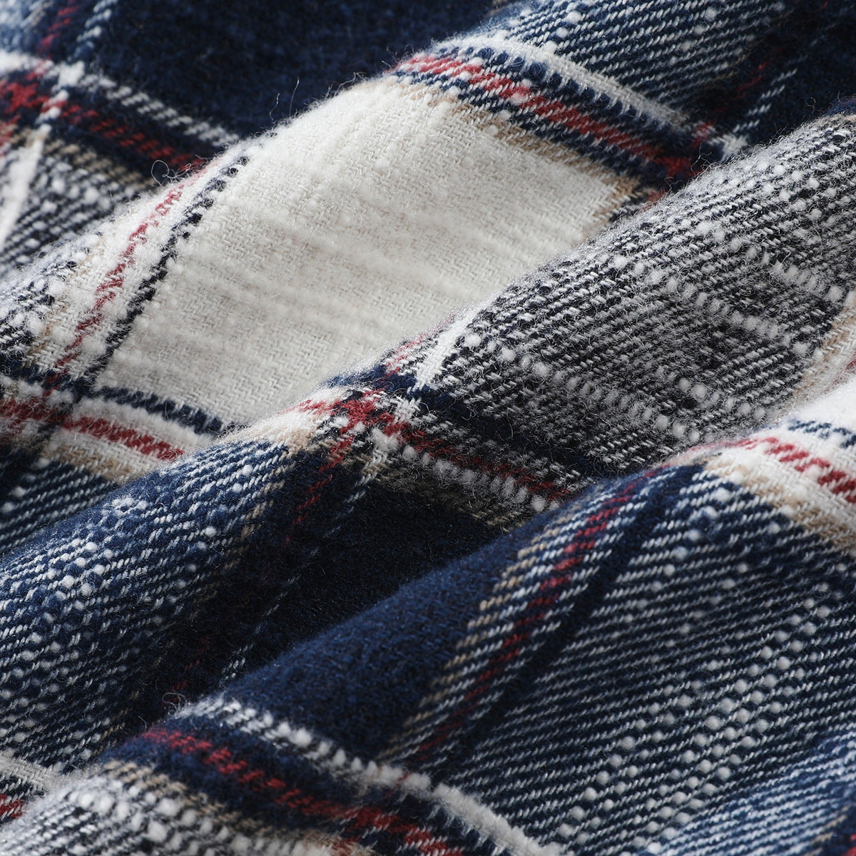 Macro view of textured navy, white and gray plaid fabric with thin red lines.