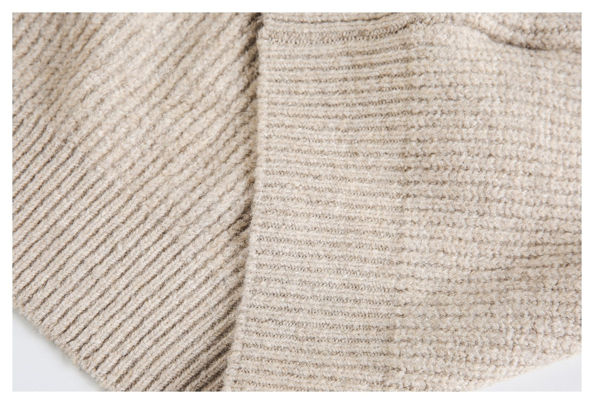 Close-up of beige knit fabric showing a folded ribbed edge and textured stitches.