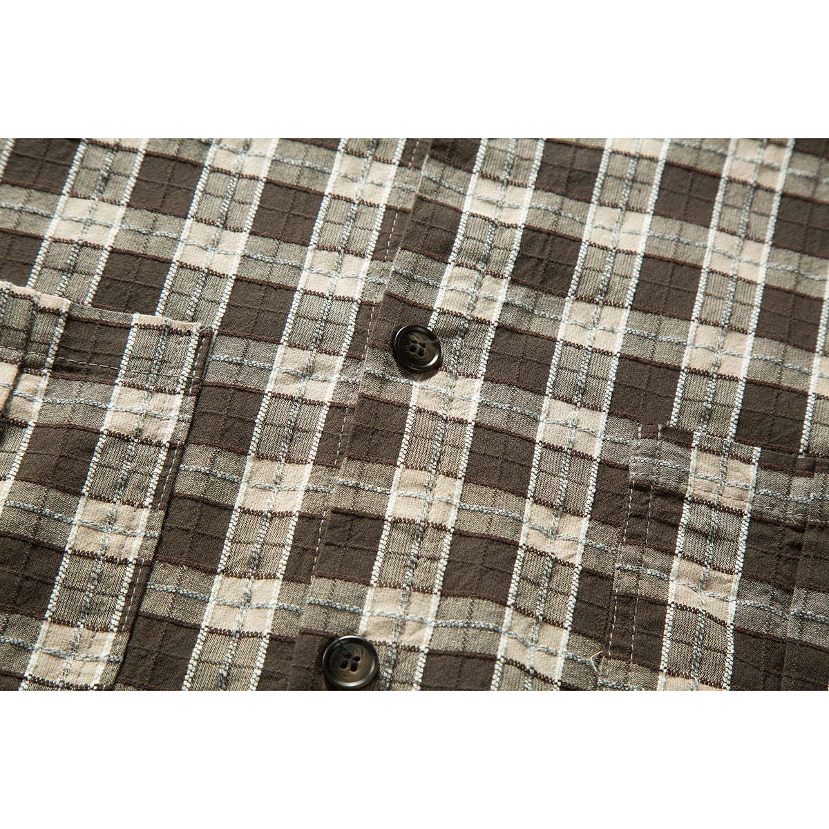 Close-up of the brown, beige and gray plaid shirt fabric, button placket and stitched pocket edge.