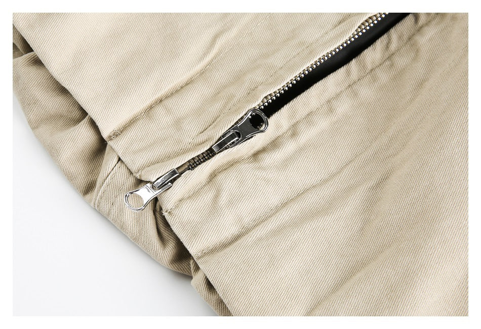 Close-up of a silver zipper with black rhinestone-trimmed tape on beige garment fabric.
