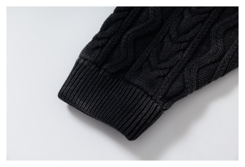 Close-up of a black cable-knit sleeve ending in a wide ribbed cuff.