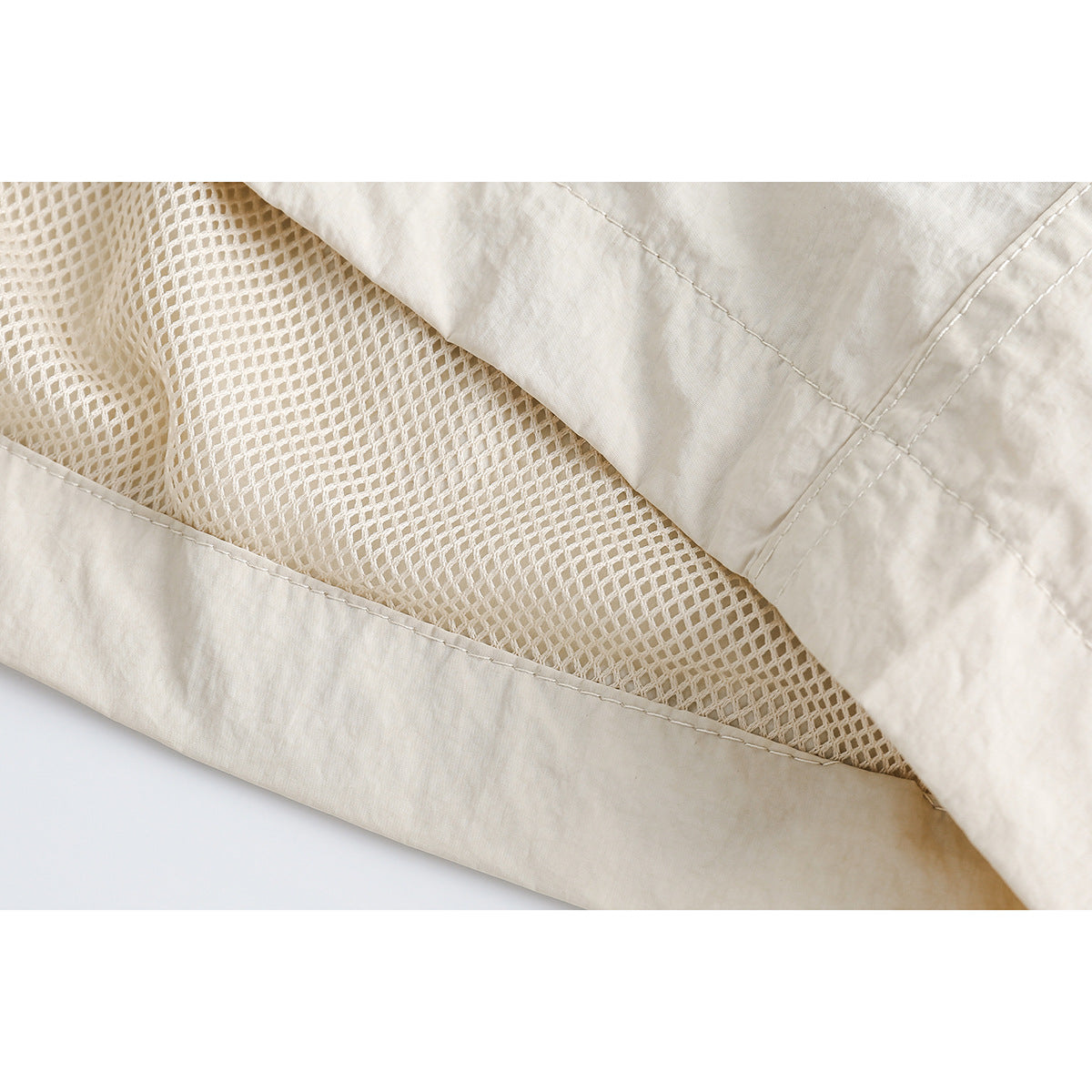 Close-up of cream shorts with diamond-mesh lining visible beneath the outer fabric.