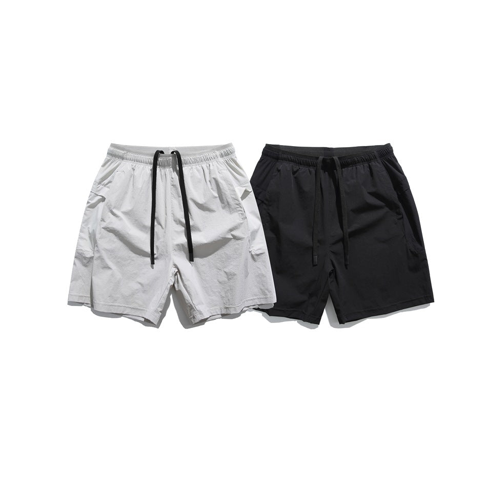 Front view of white and black shorts displayed side by side, both with elastic waists and drawstrings.