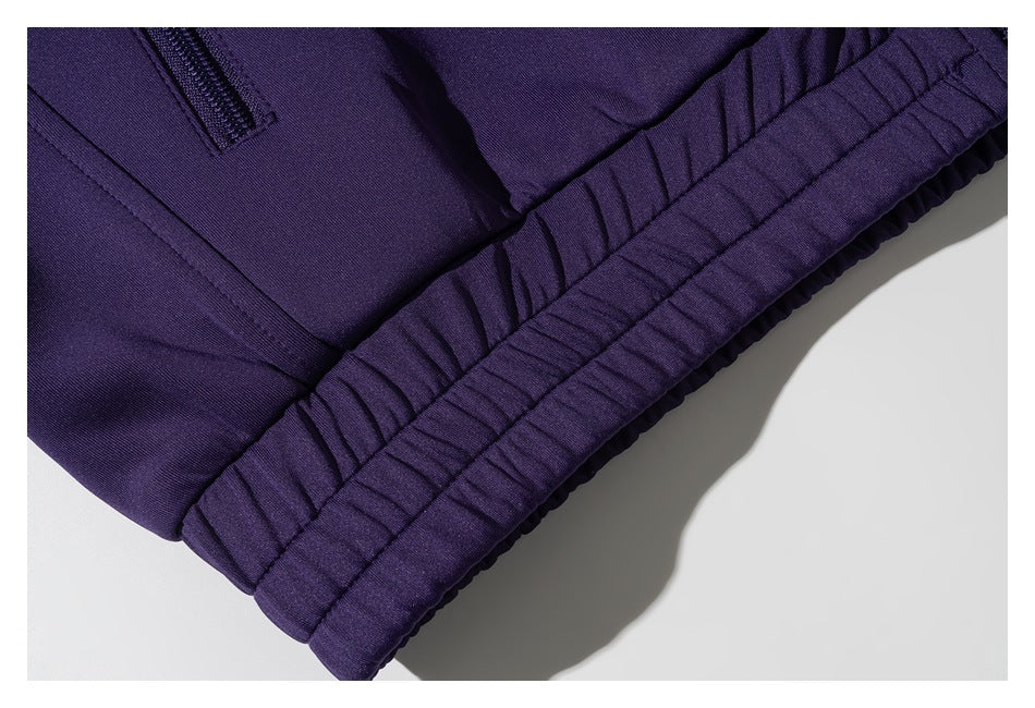 Close-up of a dark purple garment's gathered elastic hem, with part of a zipper visible.