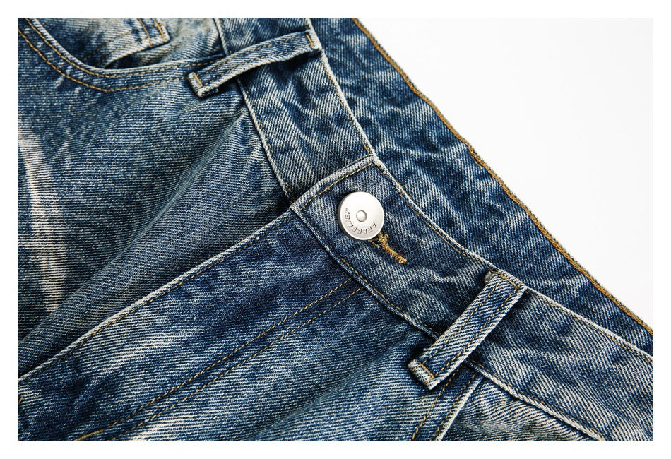 Close-up of the jeans' metal button, belt loop, and front waistband stitching.