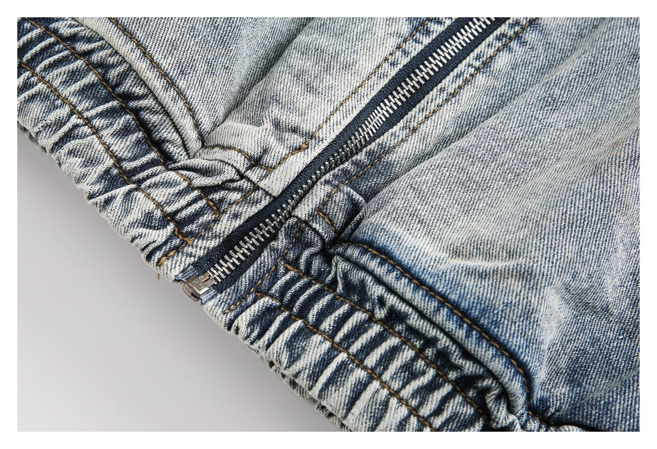 Close-up of a metal zipper and gathered elastic waistband on faded blue denim.