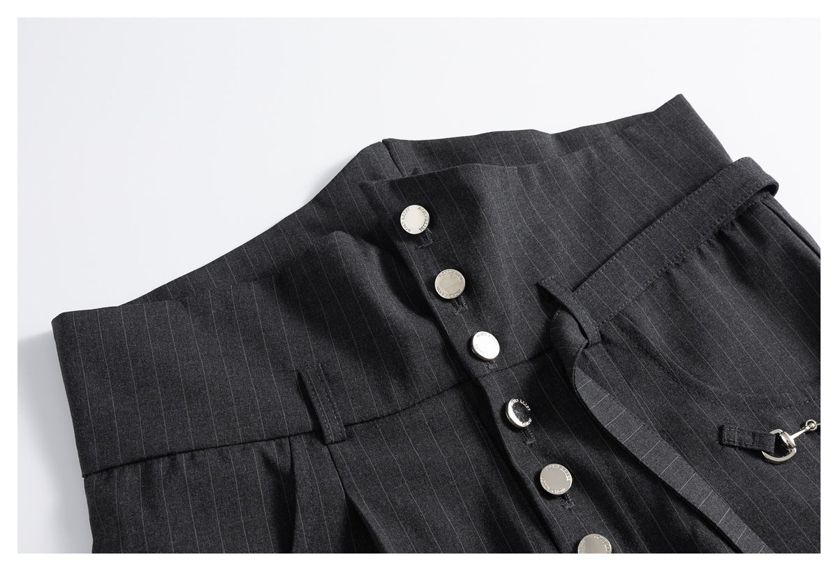 Close-up of charcoal pinstripe trousers showing the high waistband, silver buttons, belt loops and attached metal detail.