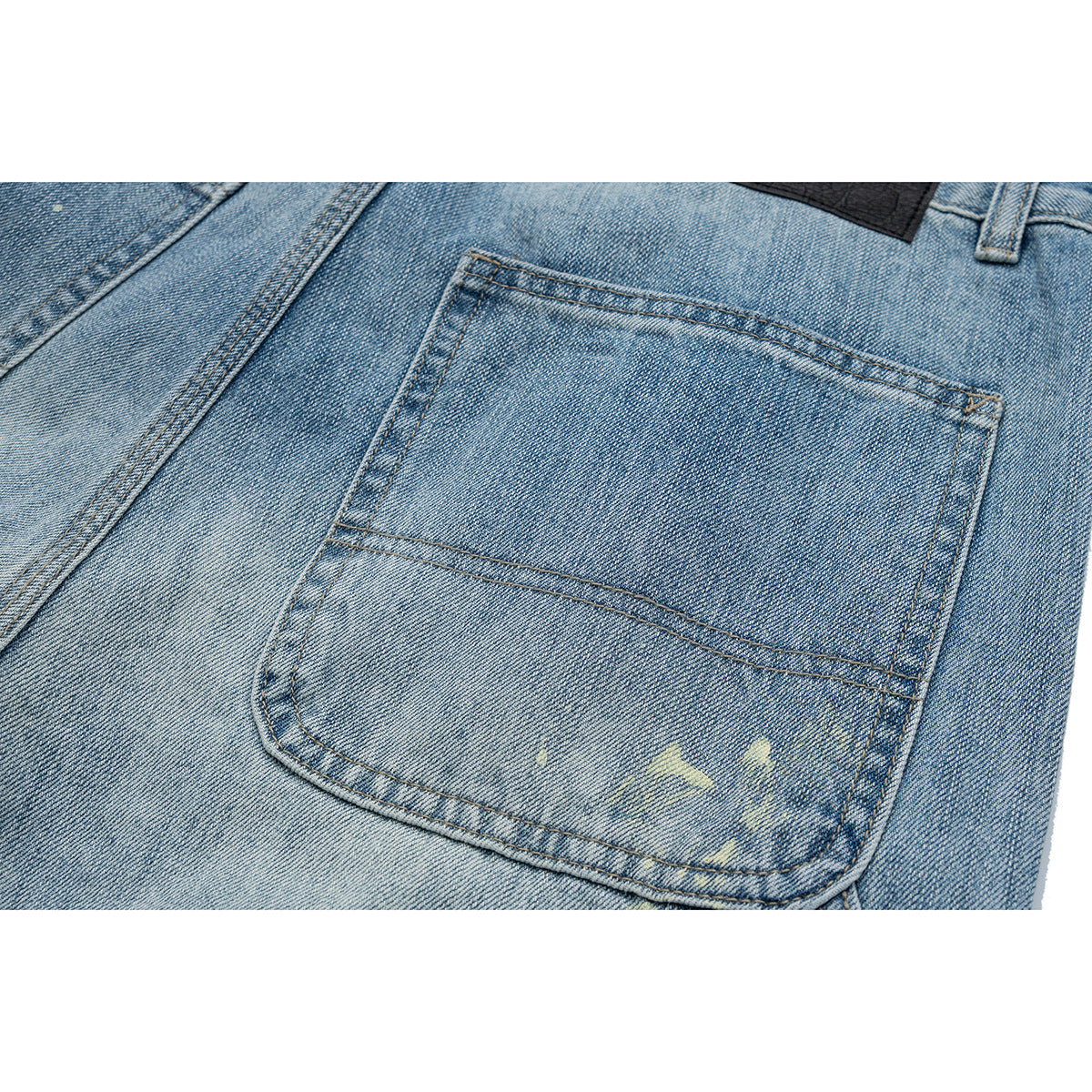 Close-up of a rear patch pocket on light blue jeans with contrast stitching and pale distressed marks.