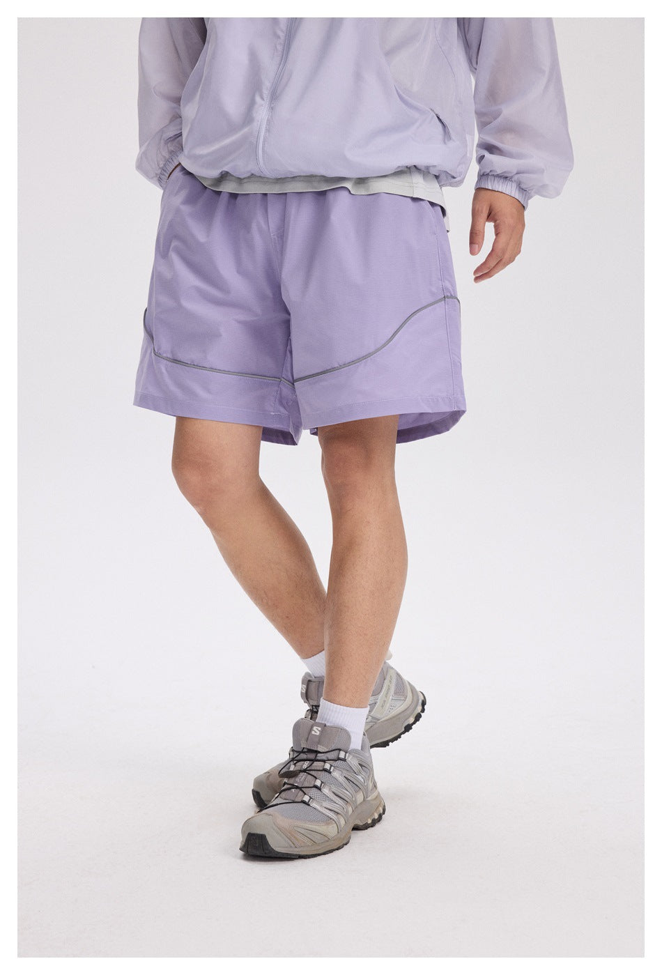 Front view of a person wearing lavender shorts with curved gray piping and wide hems.