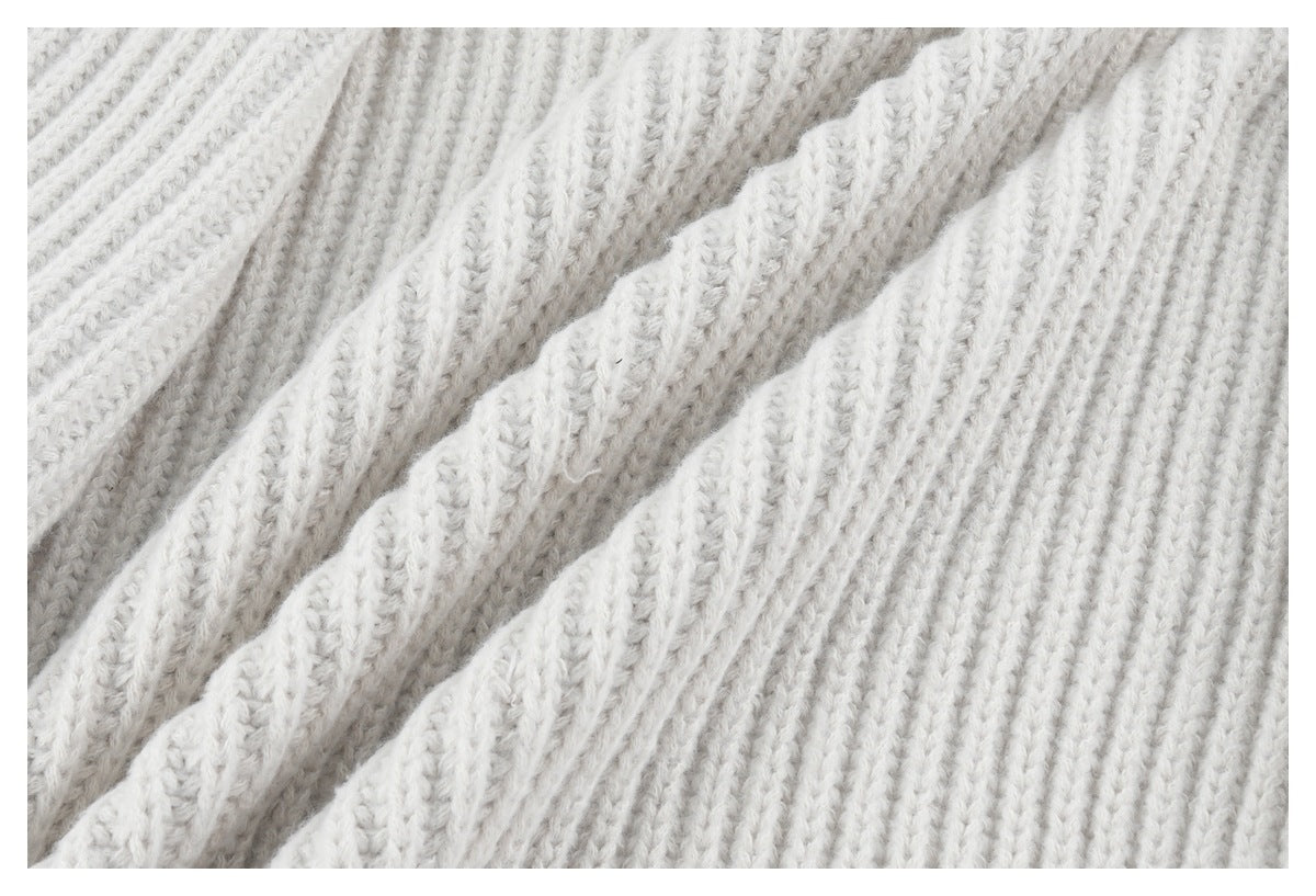 Extreme close-up showing the off-white sweater's thick ribbed knit texture.