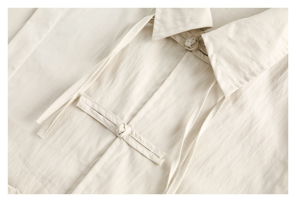Cream shirt front detail showing a knotted frog closure and narrow ties.
