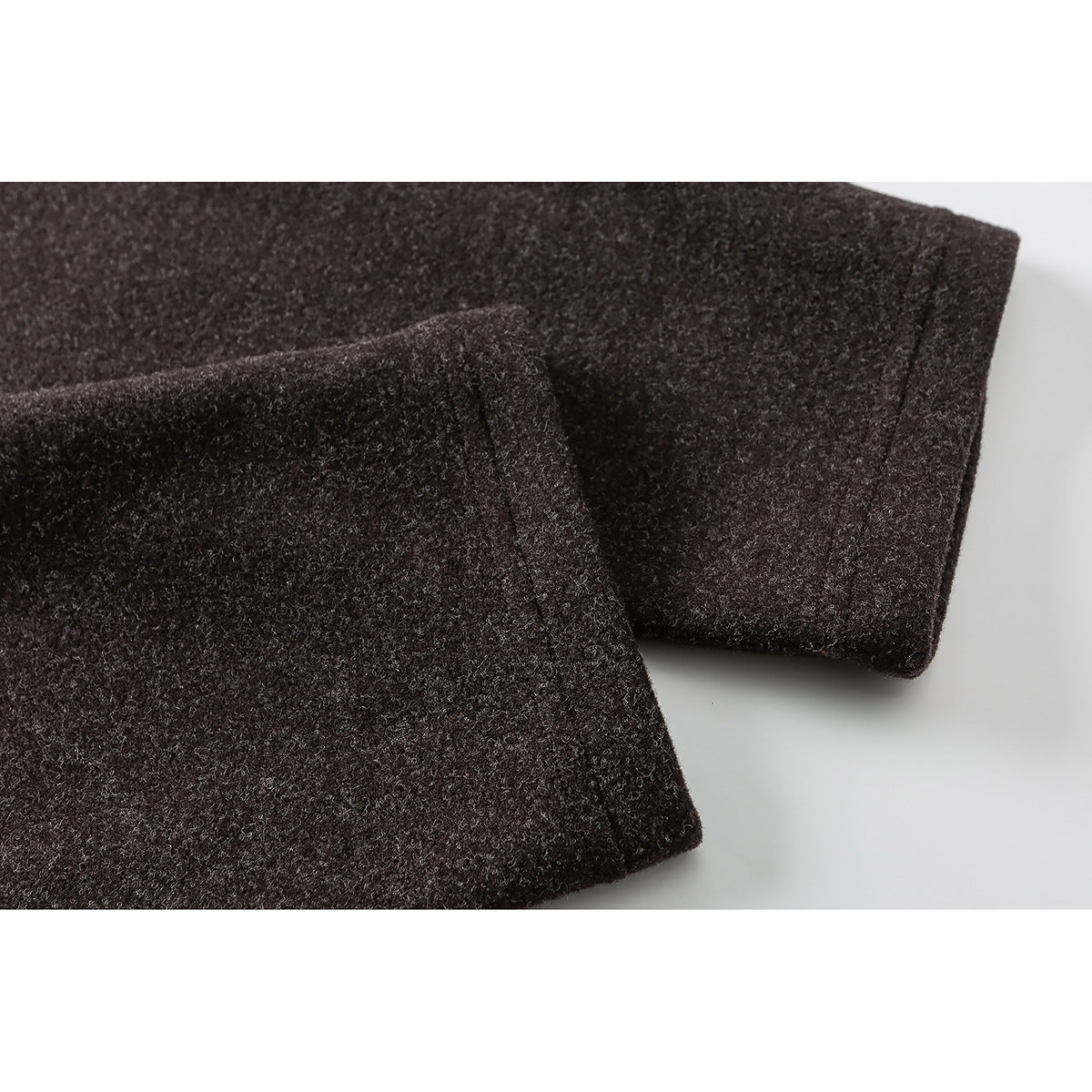 Close-up of a dark brown heathered sleeve cuff with a stitched edge.
