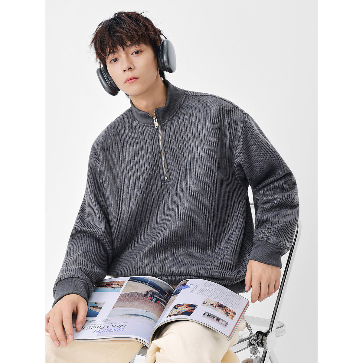 Model wearing a charcoal gray textured knit pullover with a short zip and stand collar.