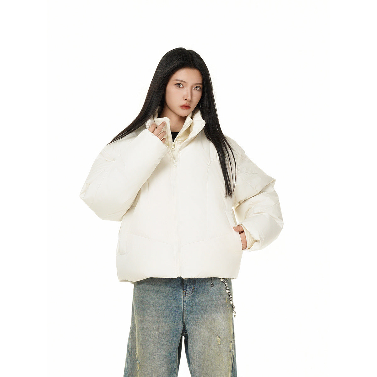 Closer front view of a model wearing an ivory puffer jacket zipped to the collar with wide sleeves.