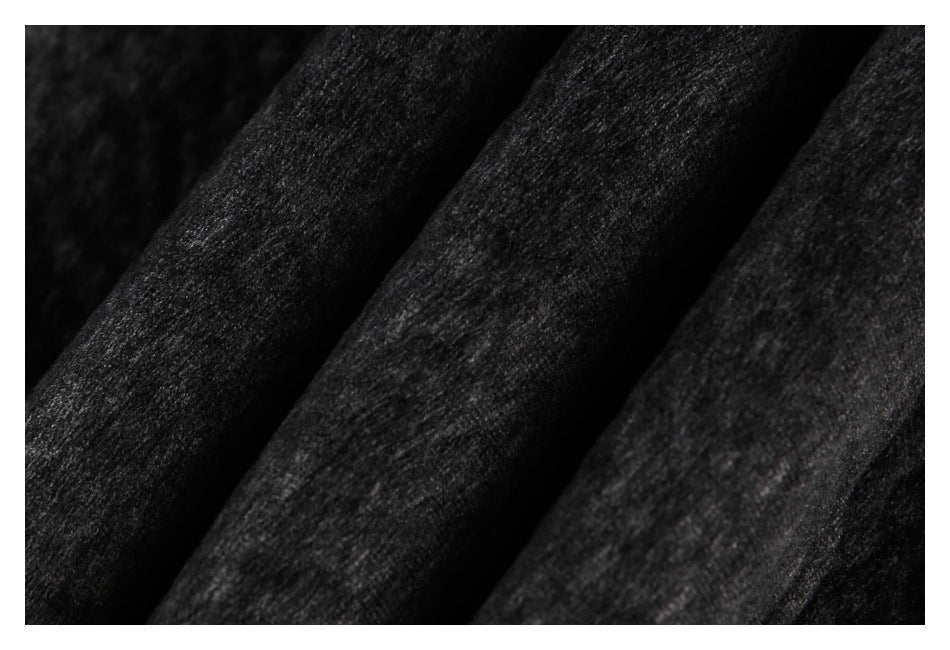 Close-up of dark charcoal-black fabric with a mottled texture and diagonal folds.