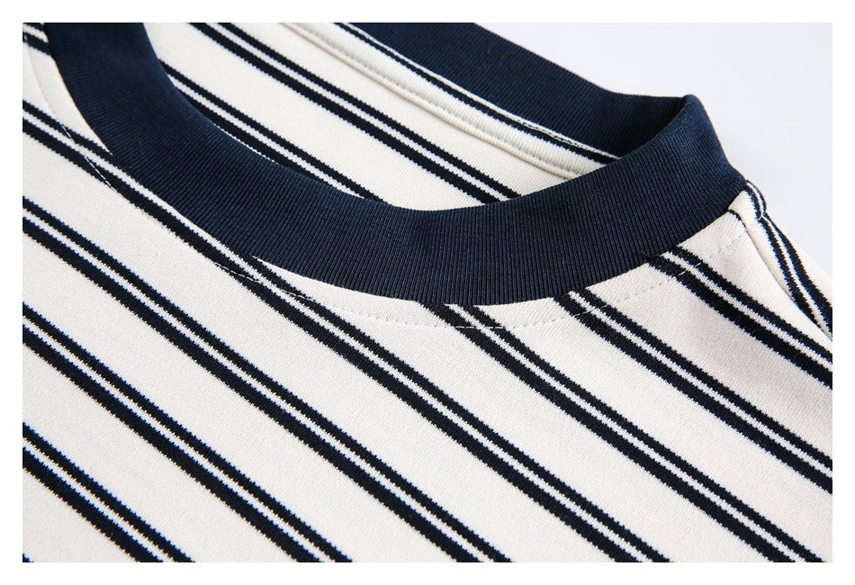 Close-up of a navy ribbed crew neck and striped white shirt fabric.