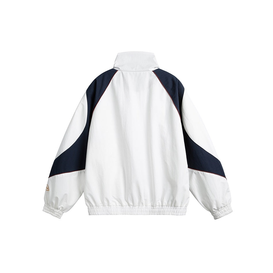 Back view of a white track jacket with navy curved sleeve panels, a high collar and elastic cuffs and hem.