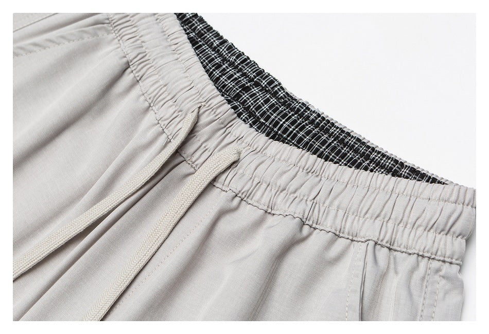 Close-up of light-gray and black-and-white plaid elastic waistbands; the gray pair has a matching drawstring.
