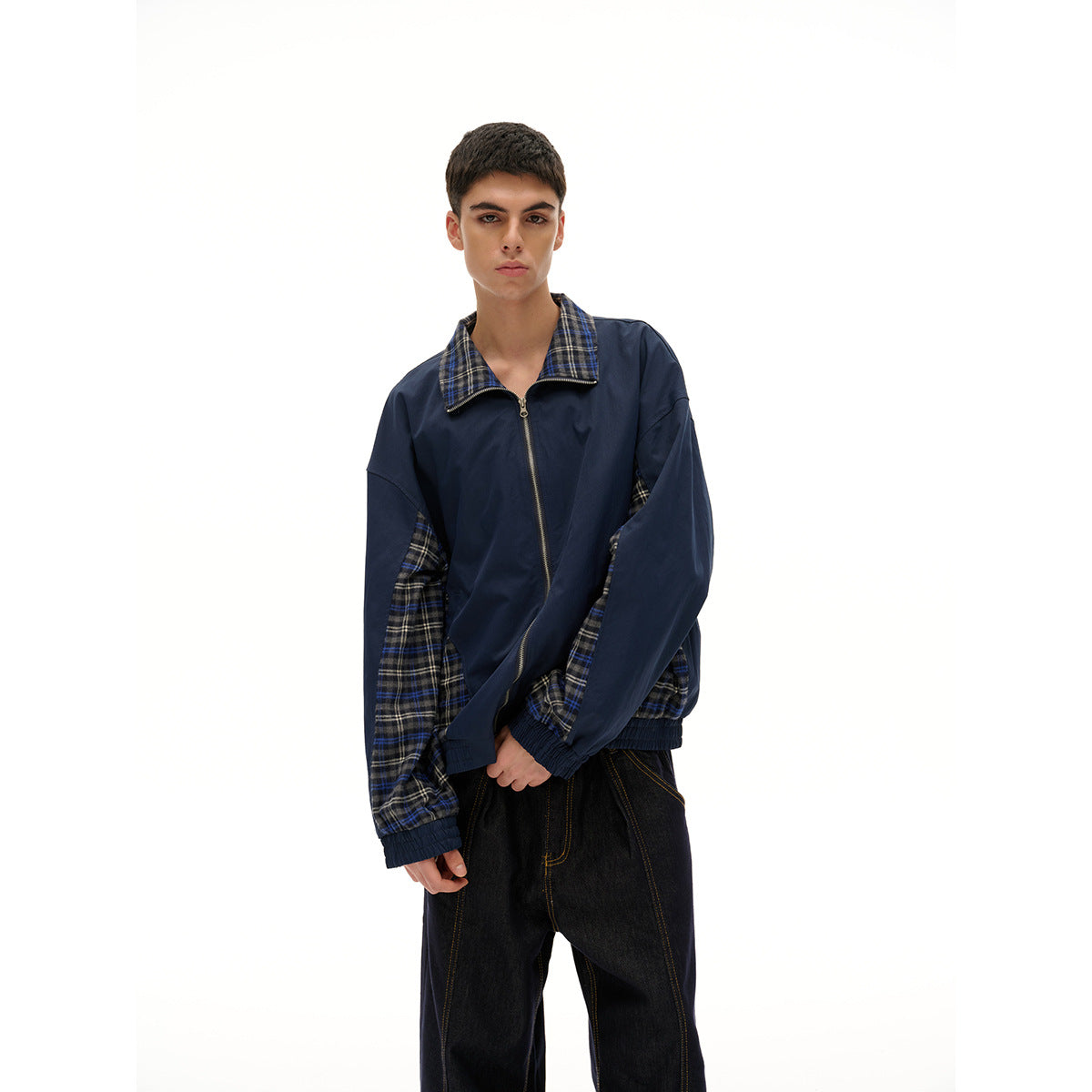 Closer view of a model wearing a navy zip-front jacket with a plaid collar and plaid sleeve and side panels.