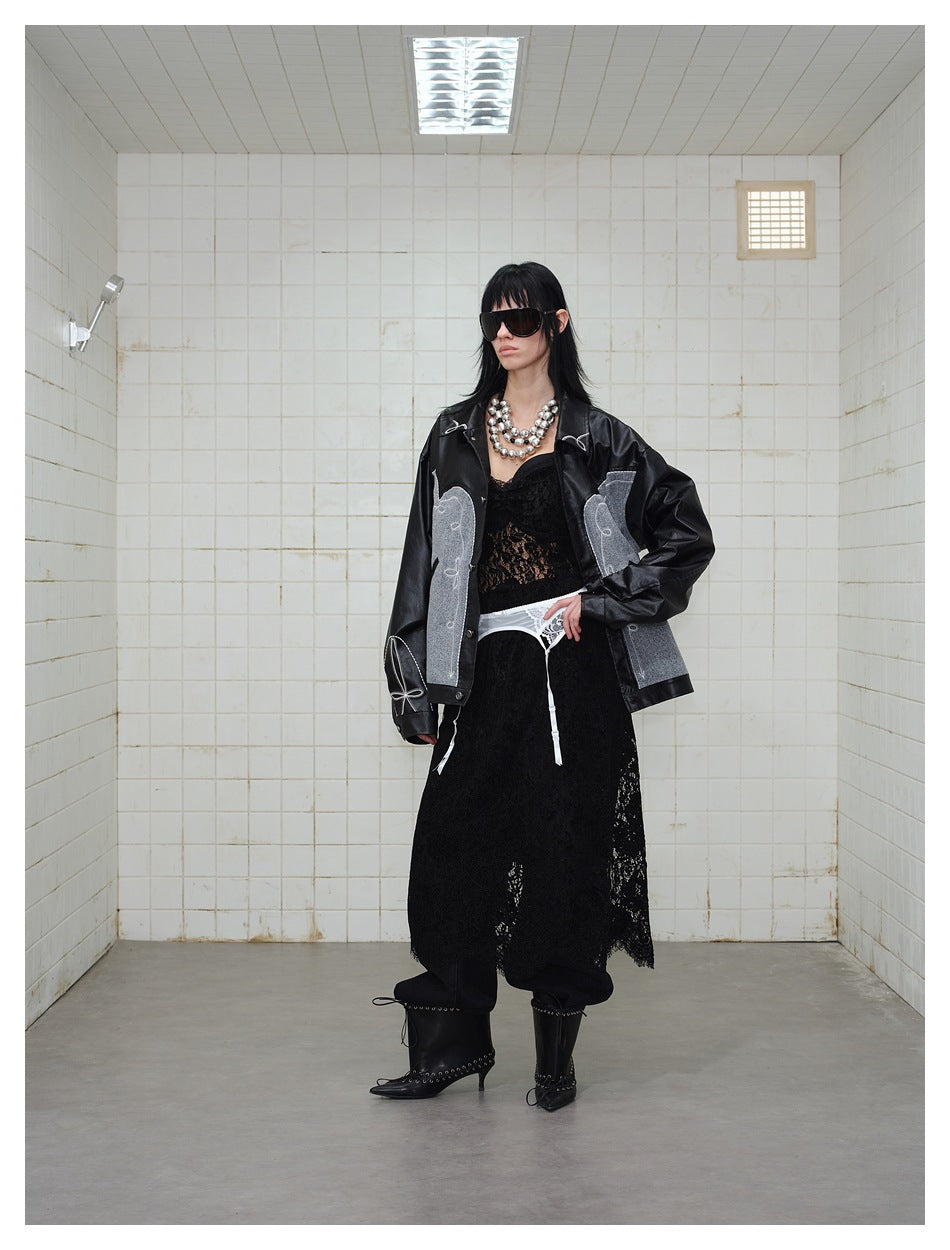 Model wearing a black jacket with gray embroidered panels, styled with a black lace skirt and boots.