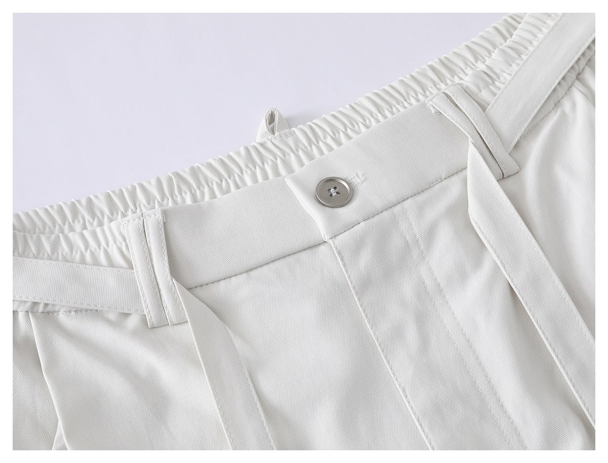Close-up of white shorts showing the elastic waistband, button, belt loops, and long waist ties.