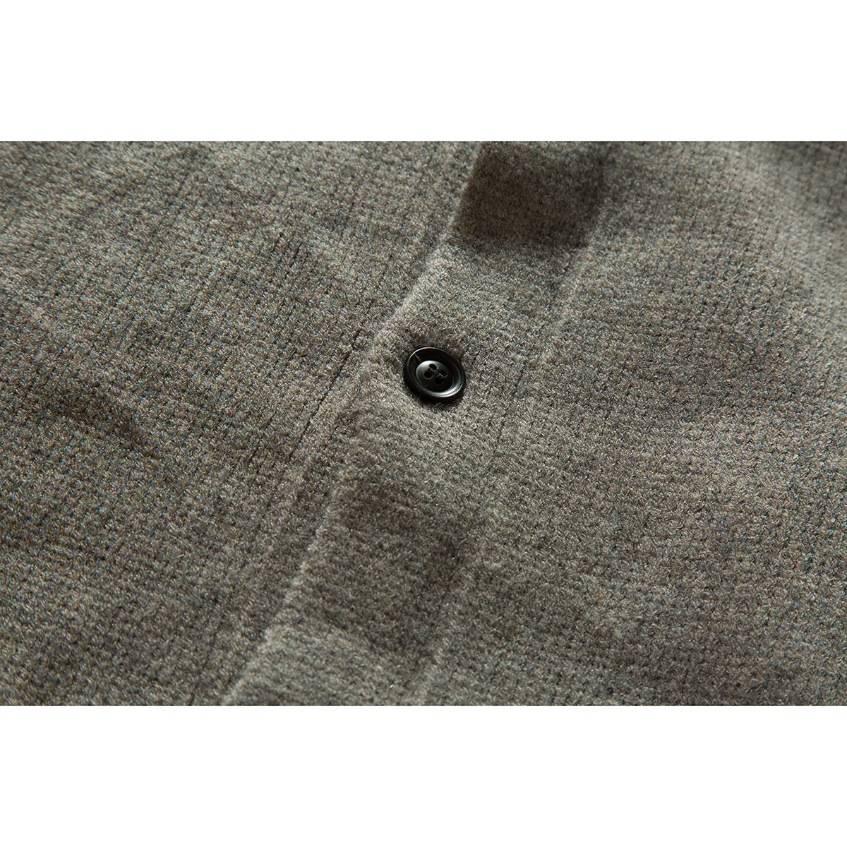 Close-up of a black button on the gray knit cardigan, showing the textured knit fabric.