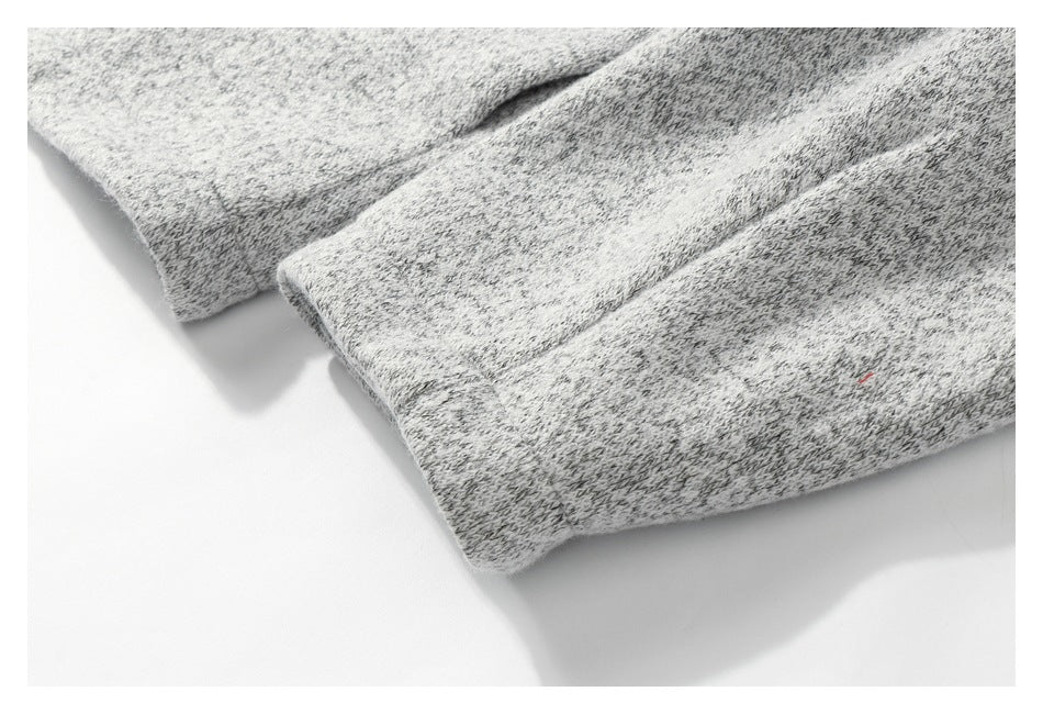 Close-up of two folded edges or cuffs of light gray marled knit fabric.