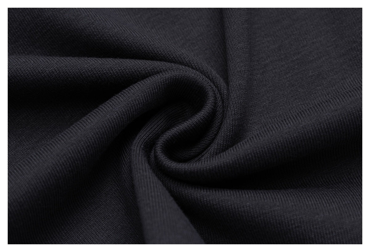 Close-up of dark charcoal fabric gathered into folds, showing its surface texture.