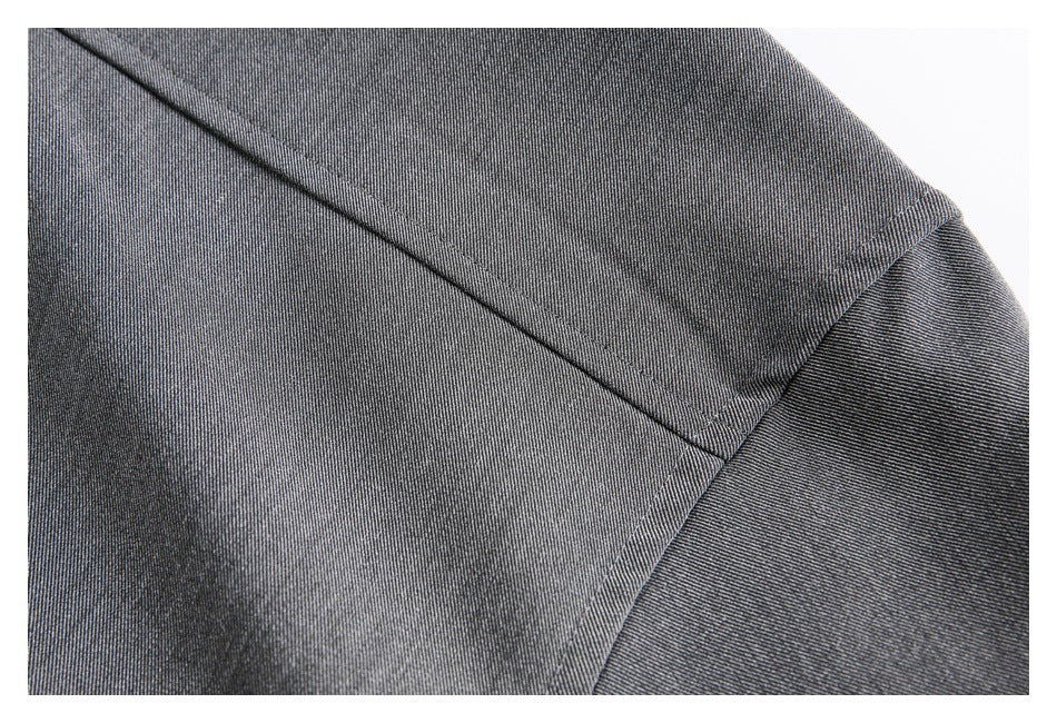 Close-up of charcoal gray garment fabric with intersecting stitched seams and a curved panel edge.