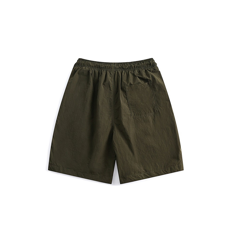 Back view of olive shorts with an elastic waistband and a single patch pocket.