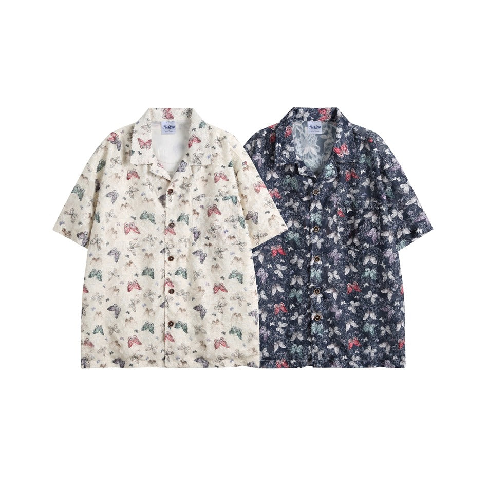 Two short-sleeve button-up shirts shown together: one cream with a multicolor butterfly print and one navy with the same